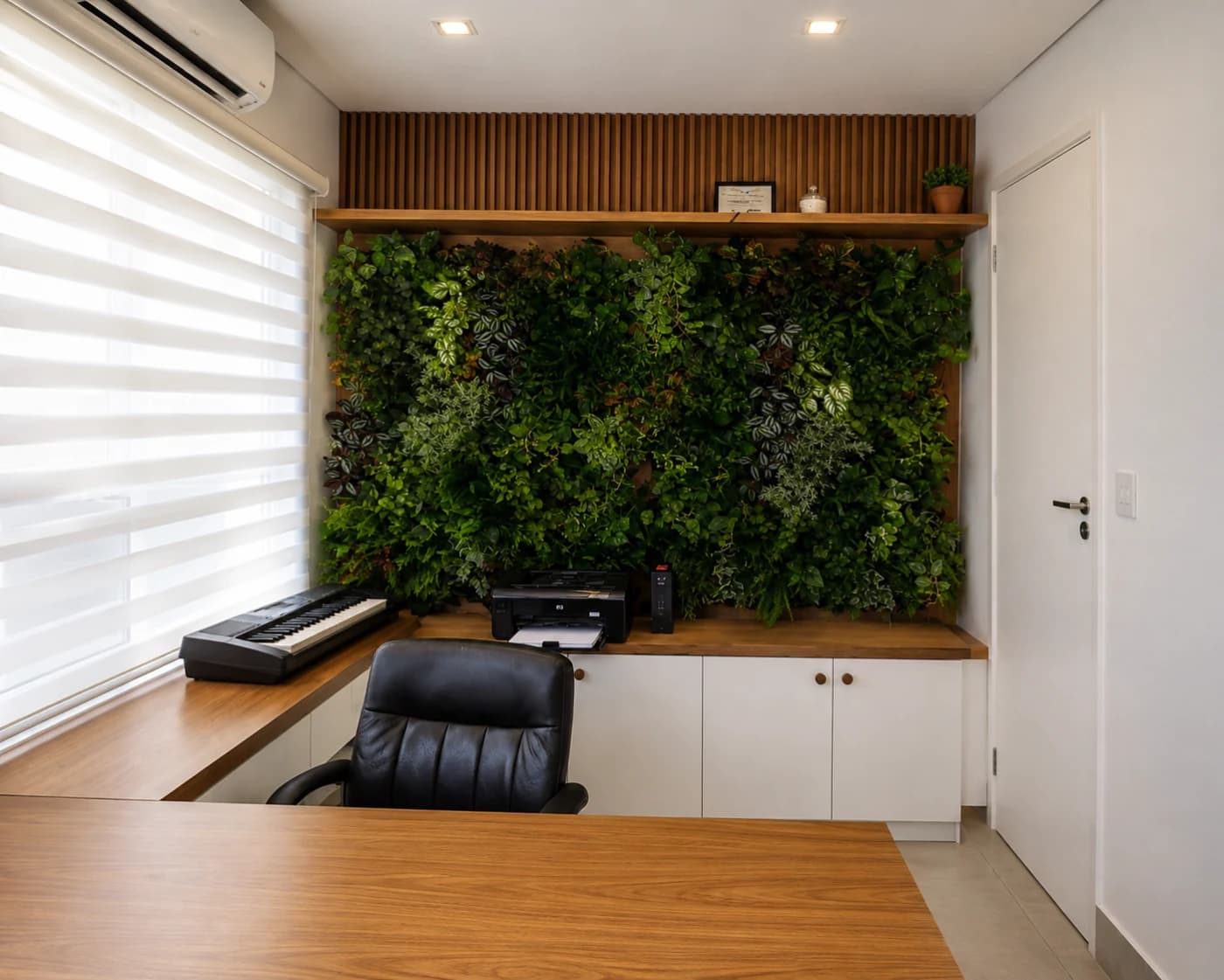 Sala de escritório com jardim vertical de folhagens atrás da bancada de trabalho