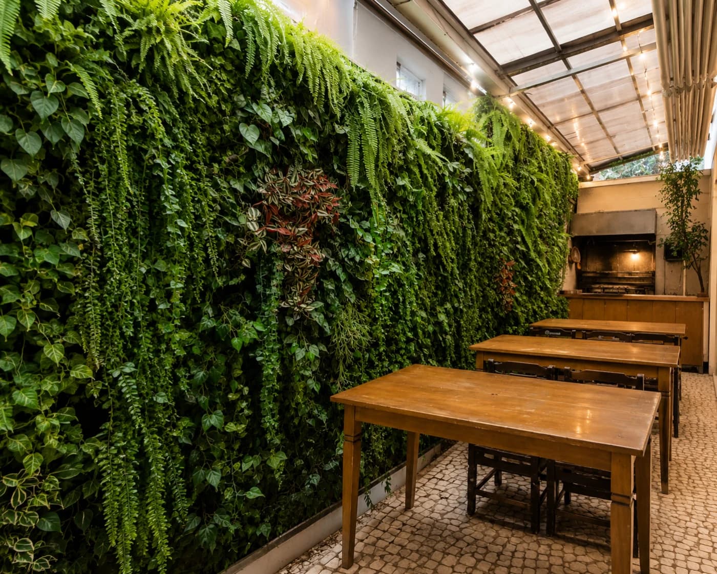 Salão de restaurante com parede inteira de samambaias e trepadeiras permanentes